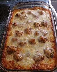 a casserole dish with meatballs and cheese in it sitting on the stove