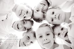 a group of young children standing in a circle looking up at the camera with their heads together