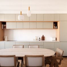 a table and chairs in a room with white walls, wooden flooring and cabinets