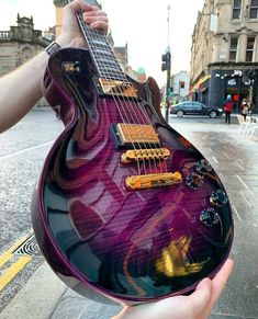 a person holding a purple guitar on the street