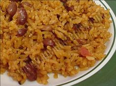 a white plate topped with rice and beans next to a green tablecloth covered table