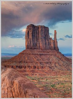 a large rock formation in the desert under a cloudy sky