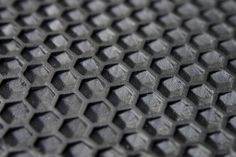 close up view of black hexagonal pattern on the surface of a piece of metal