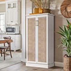 a kitchen with white cabinets and wood flooring next to a potted palm tree