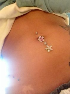 a woman's belly is adorned with pink and white flowered jewelry on her right side