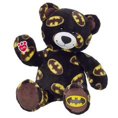 a black and yellow teddy bear with a batman symbol on it's chest, sitting in front of a white background