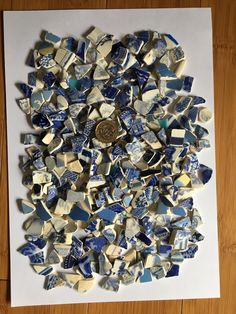 a pile of blue and white tiles sitting on top of a wooden floor next to a coin