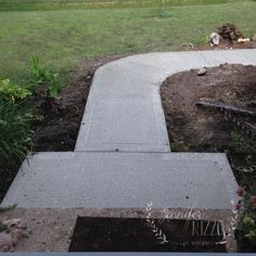 a cement walkway in the middle of a garden