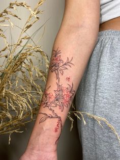 a woman with a tattoo on her arm holding a flower in one hand and a plant in the other