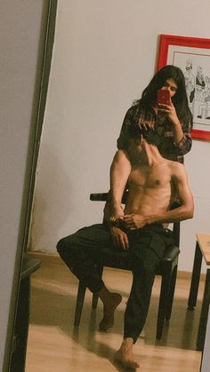 a man taking a selfie in front of a mirror with his shirtless body