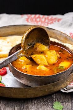 a ladle full of food sitting on top of a table next to some pita bread