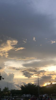 many people are sitting on the grass and watching the sun go down in the distance