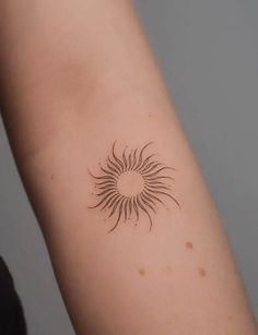 a woman's arm with a small sun tattoo on the back of her arm