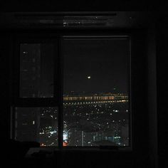 a window with the view of a city at night from it's windowsill