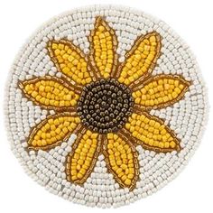 a yellow and white beaded broochle with a flower on the center, surrounded by beads