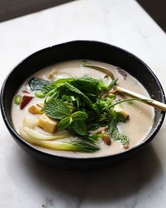 a black bowl filled with soup and vegetables