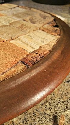 a close up of a wooden table with papers on it and a bowl in the background