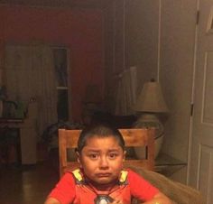 a young boy sitting at a table with food in front of him