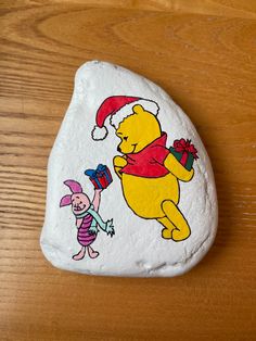 a rock painted to look like winnie the pooh and piggy with santa's hat on