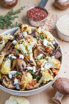 a white bowl filled with cauliflower and mushrooms next to other ingredients on a wooden table