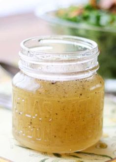 a glass jar filled with liquid sitting on top of a table next to a salad