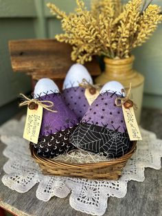 three purple and black fabric birds sitting in a basket on top of a wooden table