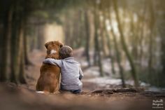 a boy hugging his dog in the woods