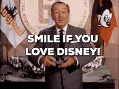 a man standing in front of two flags with the words smile if you love disney