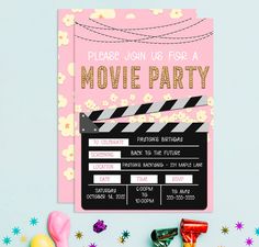 a pink movie party ticket card with candy and streamers on the table next to it