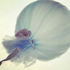 a woman in a white dress is flying through the air with a blue skirt on