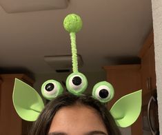 a woman with long hair wearing a green headband and eyeballs on top of her head