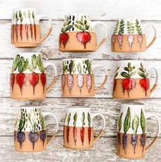 a group of coffee mugs painted with different plants and hearts on them sitting on a white wooden surface