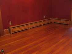 an empty room with red walls and wooden floors