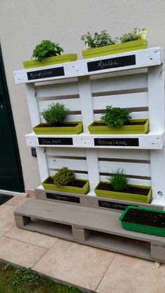 several planters are placed on the side of a building with plants growing out of them