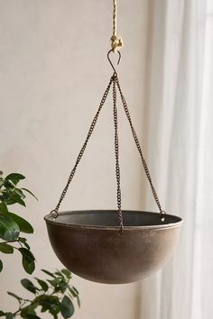 a hanging planter with chains attached to the top and bottom, in front of a window