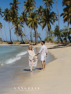 a man and woman holding hands walking on the beach with palm trees in the background