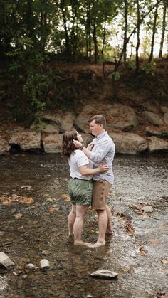 a man and woman standing in the middle of a river holding each other's hands