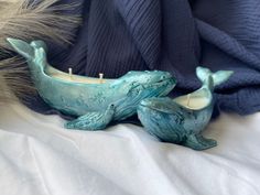 two ceramic whale candlesticks sitting on top of a bed