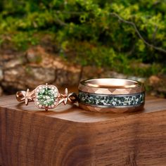 two wedding bands sitting on top of a wooden table next to each other with green plants in the background