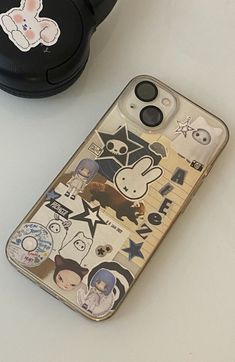 an iphone case with stickers on it next to headphones and a cell phone