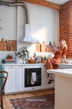 a woman is sitting on the kitchen counter