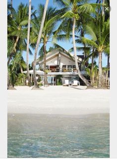 a house on the beach surrounded by palm trees and clear blue water with white sand