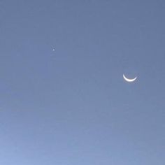 the moon and venus are visible in the blue sky