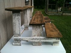 two wooden benches sitting next to each other on a white table in front of a building