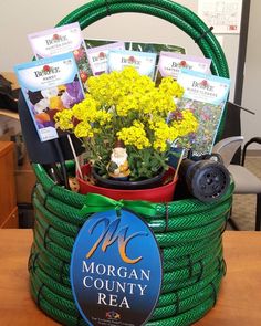 a green basket filled with yellow flowers on top of a wooden table