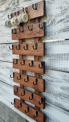 a wooden wall mounted with several hooks and two beer cans on it's side