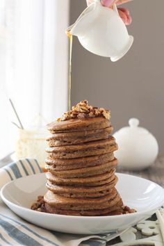 a stack of pancakes with syrup being poured on top