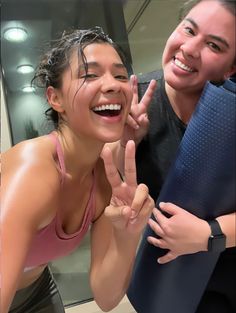 two women are smiling and making the peace sign with their hands in front of them