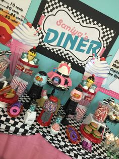 a table topped with lots of cakes and cupcakes next to a sign that says simply diner