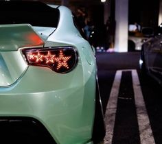 two cars parked next to each other in a parking lot at night with lights on